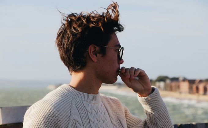 A man wearing a hair system looking at the sea 